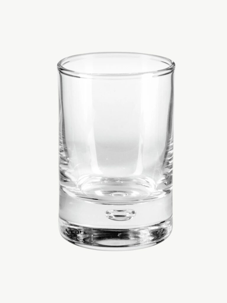 Kleines Schnapsglas aus Glas auf hellem Hintergrund