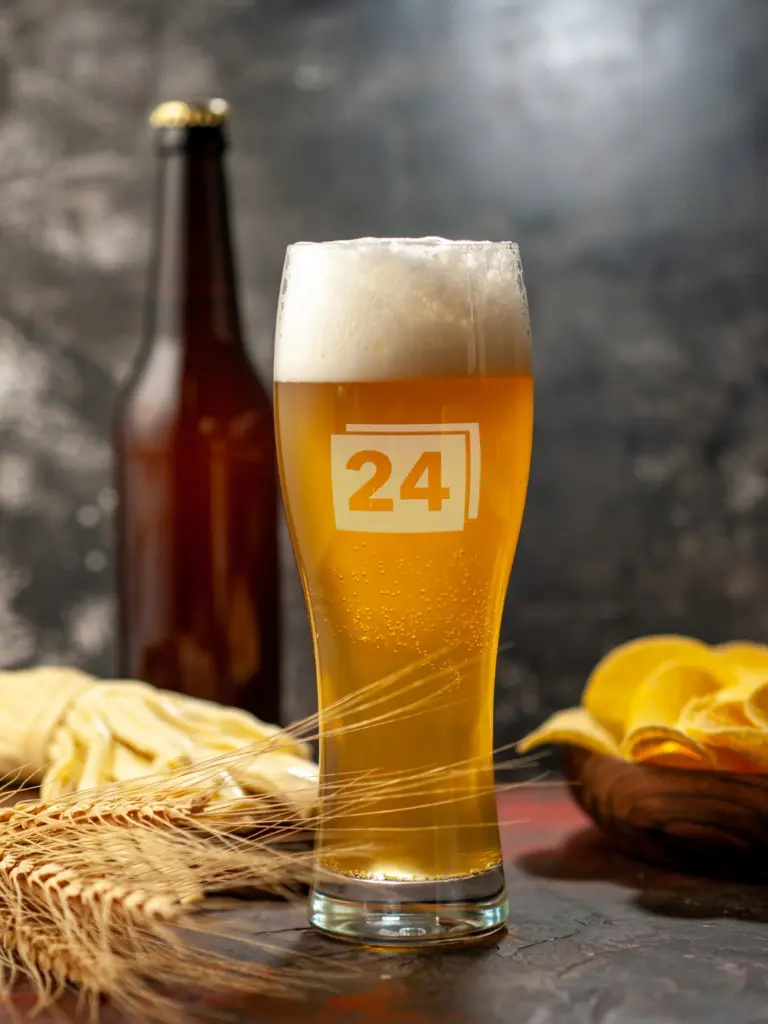 Weizenglas mit Gravur „24“, gefüllt mit Bier und Schaumkrone